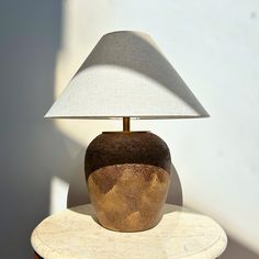 a lamp sitting on top of a wooden table next to a white and brown vase