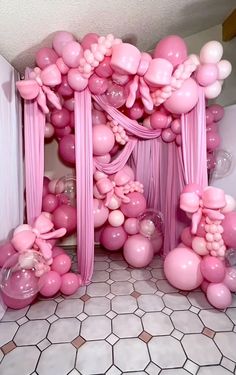 pink balloons and bows decorate the entrance to a room that is decorated with white tiles