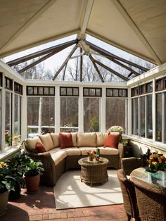 an enclosed patio with wicker furniture and potted plants