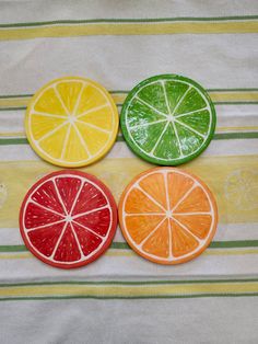 three slices of orange, lemon and grapefruit on a striped tablecloth with green and yellow stripes