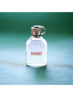 a bottle of perfume sitting on top of a blue table next to a green wall