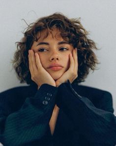 a woman with her hands on her face and looking at the camera while sitting down