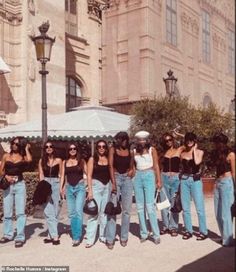 a group of young women standing next to each other in front of a tall building