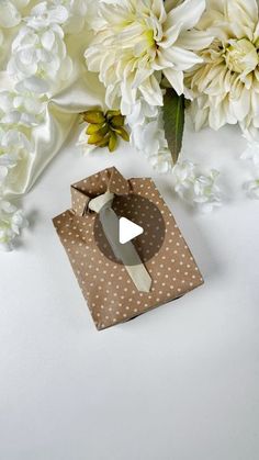 some white flowers and brown napkins on a white table with a piece of paper in the middle