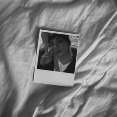 a black and white photo of a woman laying on a bed with her hand to her face