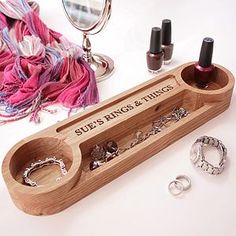 a wooden jewelry holder with rings and ring holders on the table next to it is an assortment of accessories