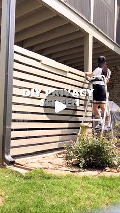 a woman painting the side of a building that says diy privacy screen on it