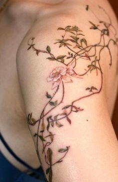 a woman's arm with flowers and vines tattooed on the side of her body