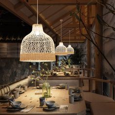 a wooden table topped with lots of plates and bowls next to a lamp hanging from the ceiling