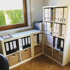 a room with some bookshelves filled with files and folders next to a window