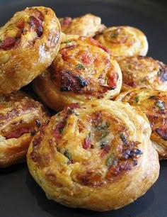 several small pastries sitting on top of a black plate next to each other in a pile