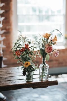 two vases filled with flowers sitting on top of a wooden table