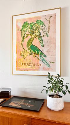 a painting hanging on the wall above a desk with a potted plant in front of it