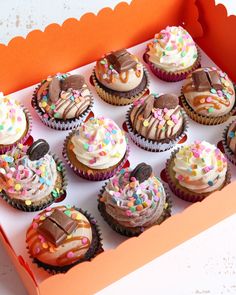 a box filled with cupcakes covered in frosting and sprinkles