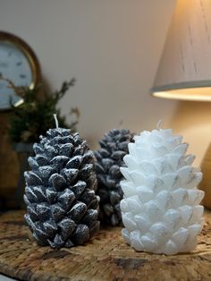 three pine cones sitting on top of a wooden table next to a lamp and clock