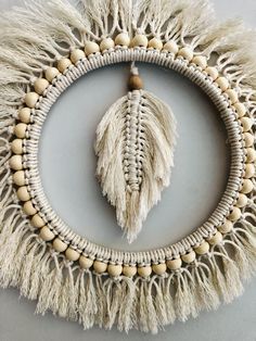 a white circular wall hanging with tassels and beads