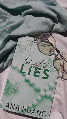 a book and glasses laying on top of a bed