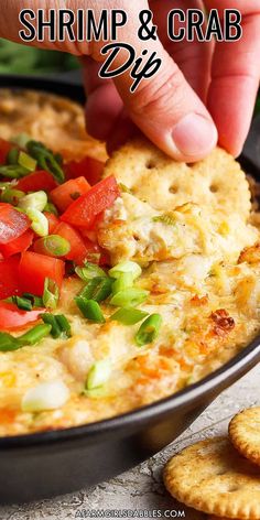 a person dipping some food into a pan with crackers on the side to eat