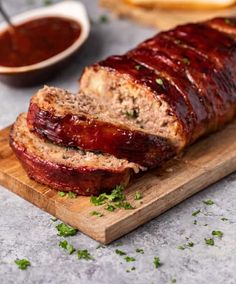 sliced meatloaf on a cutting board with ketchup and bread in the background