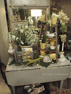 an old dresser with flowers and other items on it in front of a brick wall