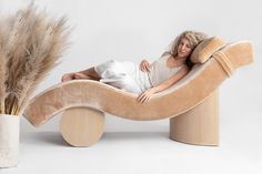 a woman is laying on a couch made out of wood