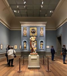 people are looking at art on display in an old museum with blue walls and wooden floors