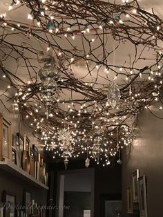 a room filled with lots of lights and branches hanging from it's ceiling fixture