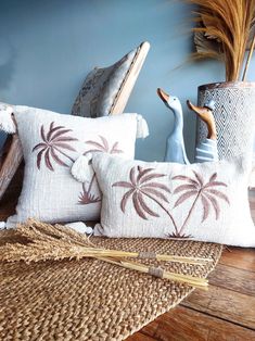 two decorative pillows with palm trees on them next to a basket and some other items