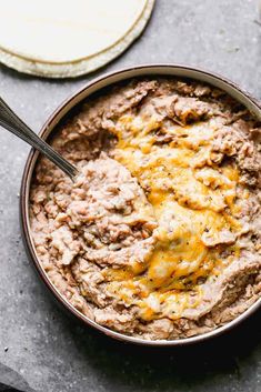 a bowl filled with meat and cheese sitting on top of a table next to bread