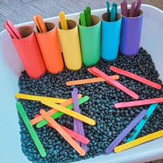 there are many different colored toothbrushes in the container on the table with beans