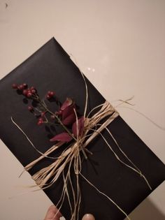 a person holding up a piece of black paper with flowers on it and twine