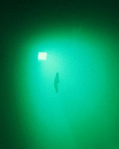 a person standing under a green light in the dark