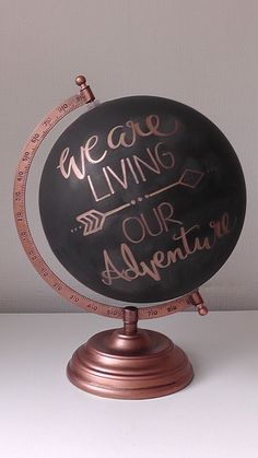 a black and copper globe with the words we are living our adventure written on it