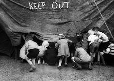 an old black and white photo of people surrounding a tent with the words keep out written on it