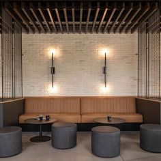 an empty room with three round tables and two stools in front of the wall