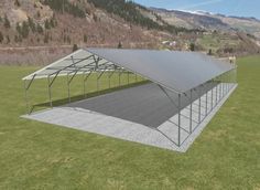 a large metal structure sitting in the middle of a field with mountains in the background