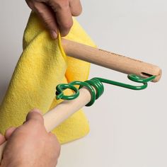 a person holding a pair of scissors and a yellow towel on a white surface with green handles