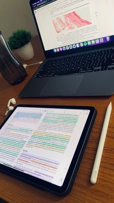 an open laptop computer sitting on top of a wooden desk next to a white pen