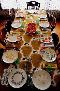 the table is set with many plates and place settings for four people to sit at