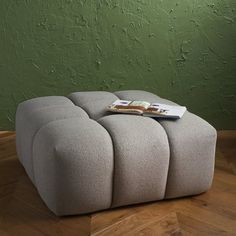 a small ottoman sitting on top of a hard wood floor next to a green wall