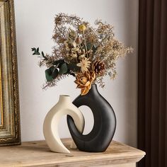 two vases with flowers in them sitting on a table next to a framed photograph