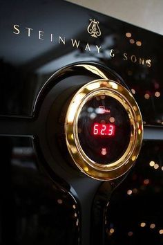 a close up of a clock on the side of a black wall with lights behind it