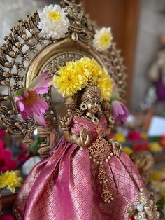 a doll with flowers in her hair sitting on a table next to other decorations and flowers