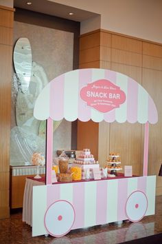 a pink and white candy cart with snacks on it