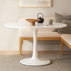 a white table sitting in front of a couch next to a painting on the wall