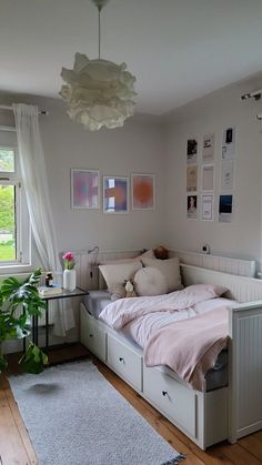 a bedroom with a bed, desk and plants on the windowsills in it