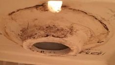 a dirty toilet bowl in a bathroom with dirt on the walls and ceiling above it