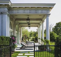 an outdoor covered patio with benches and flowers on the side walk, surrounded by greenery