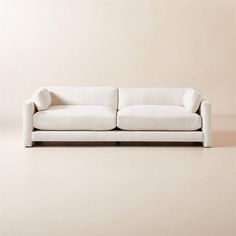 a white couch sitting on top of a floor next to a beige wall with a wooden frame