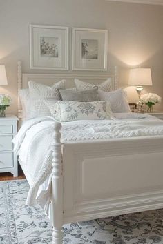 a white bed sitting in a bedroom on top of a rug next to two lamps